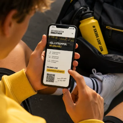 Ungdom håller upp en mobil som visar Sockgrossistens webbshop med egen säljlänk